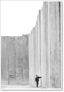 A boy reaching for a high wall in the West Bank.